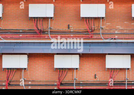 Ampia gamma di inverter per pannelli solari su una parete di fabbrica Foto Stock