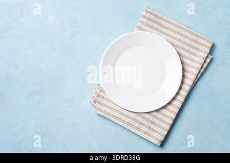 Svuotare la piastra bianca e il tovagliolo su sfondo blu Foto Stock