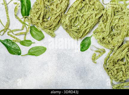 Tagliatelle di pasta verde italiana cruda fatta in casa. Spaghetti e ingredienti secchi (spinaci, farina, uova). Messa a fuoco selettiva, vista dall'alto, copia Foto Stock