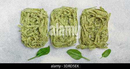 Tagliatelle di pasta verde italiana cruda fatta in casa con spinaci. Spaghetti secchi Foto Stock