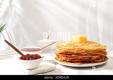 Deliziosi pancake russi con marmellata, formaggio fresco e latte su un tavolo di marmo. Colazione salutare con ingredienti, la colazione Foto Stock
