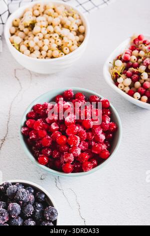 Viburnum congelato in un recipiente e altre bacche sulla vista verticale del tavolo Foto Stock