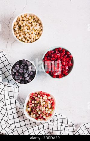 Rosso, bianco, ribes e viburno congelati in tazze sul piano del tavolo e vista verticale Foto Stock