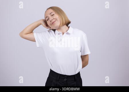 Giovane donna in camicia bianca che posa su sfondo bianco Foto Stock