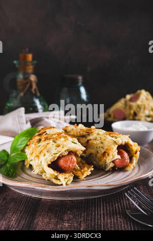 Salsicce avvolte in pancake di cavolo grattugiati su un piatto con vista verticale sul tavolo Foto Stock