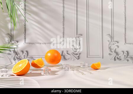 Natura morta moderna con agrumi, fette di arancio e cubetti di ghiaccio su sfondo elegante con ombre, dieta disintossicante minimalista Foto Stock