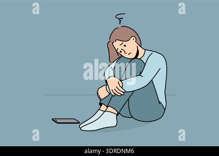 La donna triste aspetta una telefonata, sta seduta per terra e soffre di solitudine o di mancanza di amici Foto Stock