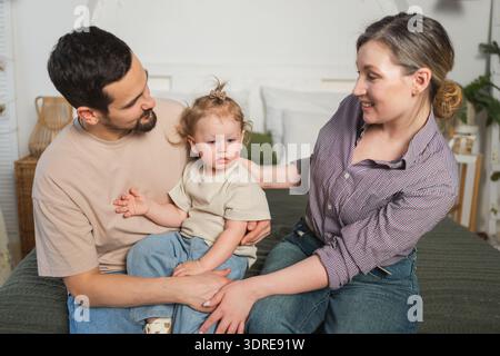Famiglia felice a casa. Madre padre bambino bambino figlia rilassarsi sul divano al coperto. Mamma papà genitori ragazzina rilassati giocando huggi Foto Stock