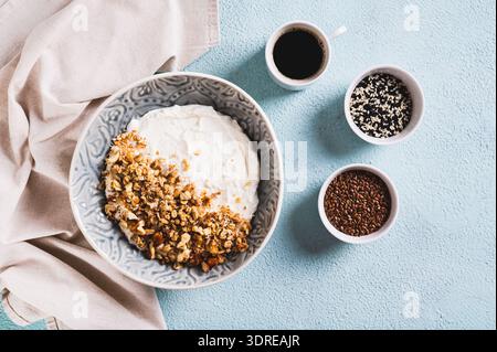 Ciotola con yogurt, muesli e noci per una colazione sana sulla vista dal tavolo Foto Stock
