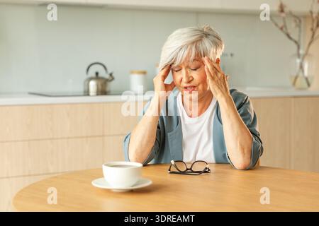 Mal di testa, infelice donna anziana di mezza età che soffre di mal di testa malata che sfrega i templi a casa. Vecchio nonno anziano maturo Foto Stock