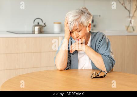 Triste stanca malata malata solitaria delusa anziana donna seduta a casa da sola. Infelice nonna matura che soffre di dolore Foto Stock