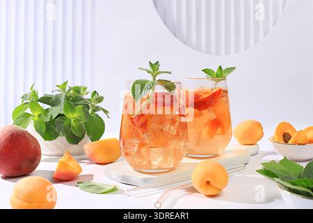 Tè alla pesca o cocktail con menta e albicocche, una ricetta per una rinfrescante bevanda estiva. Due bicchieri con limonata di frutta di pesca Foto Stock