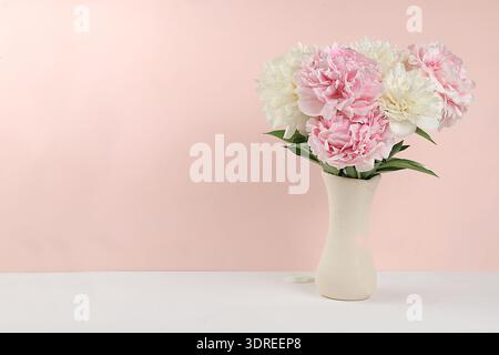 Interni di casa con elementi di arredo, splendidi rami di peonia primaverile in un vaso su sfondo chiaro, disposizione astratta dei fiori, Foto Stock