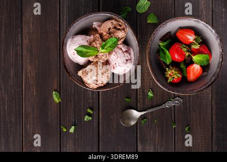 Deliziose ciotole di gelato e fragole su un tavolo di legno Foto Stock