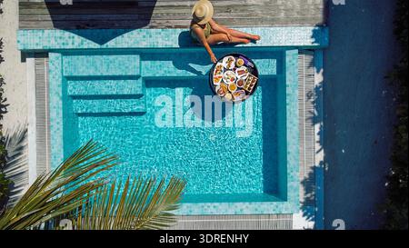 Una giovane donna in costume da bagno si rilassa in una piscina all'aperto. Vista dall'alto Foto Stock