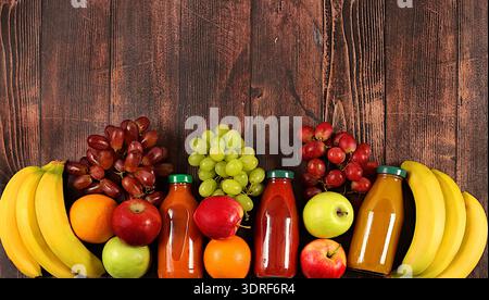 Prodotti vegani sani per uno stile di vita sano. Uva, arance, ananas, mele, banane, frutta secca e succo naturale su un legno Foto Stock
