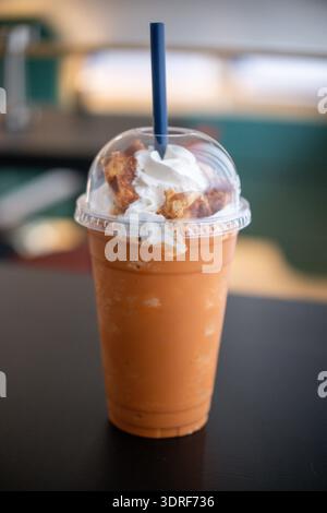Tè tailandese miscelato con panna montata, sul tavolo con sfondo sfocato Foto Stock