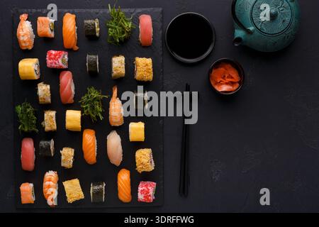 Collezione di sushi su un piatto nero con teiera verde e salsa di soia Foto Stock