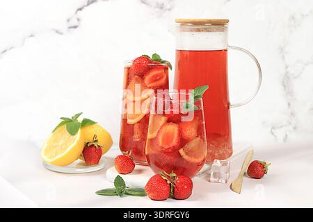 Rinfrescante cocktail estivo di limonata fatta in casa, tè freddo alle fragole con frutti di bosco, menta e limone, concetto di perdita di peso, acqua disintossicante Foto Stock