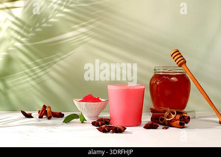 Latte matcha di latte rosa con cannella, anice e spezie al miele sul tavolo soleggiato. Il concetto di perdita di peso e medicina alternativa, Foto Stock