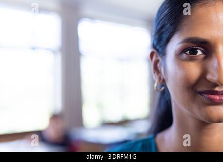 A scuola, donna sorridente in classe con studenti in background, copia spazio Foto Stock