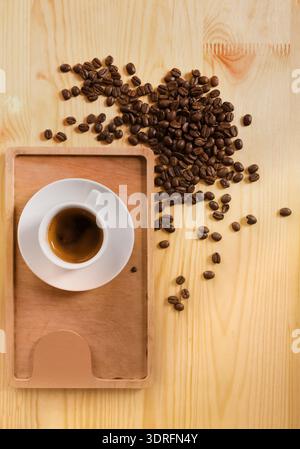 Tazza da caffè su una superficie in legno circondata da chicchi di caffè versati in un'esposizione della collezione Foto Stock