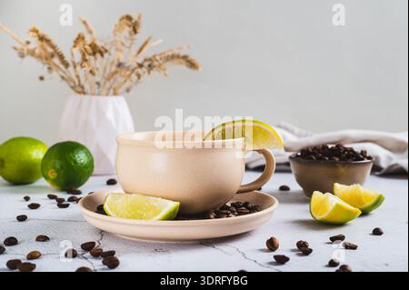 Caffè freddo con spicchi di lime in una tazza sul tavolo Foto Stock