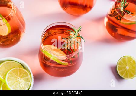 Delizioso cocktail Negroni con lime e rosmarino in bicchieri sul tavolo Foto Stock
