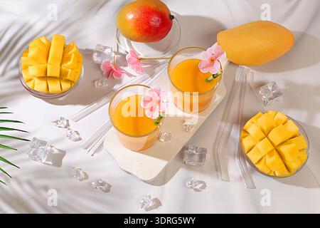 Cocktail di limonata fatto in casa, succo di frutta o frullato con mango, ghiaccio e frutta sul tavolo soleggiato, rinfrescante ricetta per bevande estive, de Foto Stock