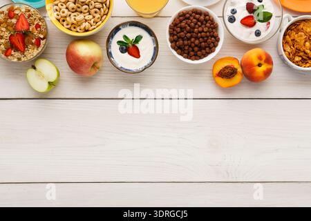 La colazione a buffet include frutta, cereali e yogurt su White Wooden Table Foto Stock