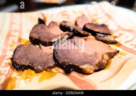 Arrosto di manzo affettato su carta con salsa, primo piano, presentazione del piatto del ristorante Foto Stock