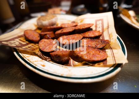 Salsicce spagnole Chorizo a fette su un piatto foderato di carta in un ristorante rustico Foto Stock