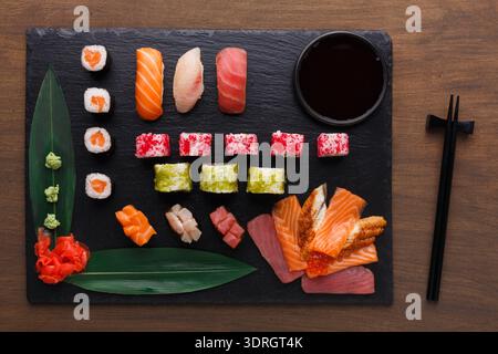 Collezione di sushi su ardesia nera con bastoncini e salsa di soia servita per cena Foto Stock