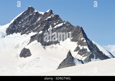 La vetta dello Jungfrau si innalza sopra il ghiacciaio innevato con l'Osservatorio della Sfinge sullo Jungfraujoch nelle Alpi Bernesi, in Svizzera Foto Stock