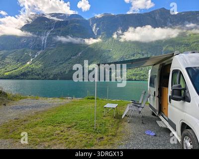 Ambientazione panoramica di camper in un tranquillo lago circondato da maestose montagne in Norvegia Foto Stock