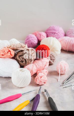 Un sacco di filati colorati, ganci a uncinetto e aghi per maglieria su un tavolo con vista verticale Foto Stock