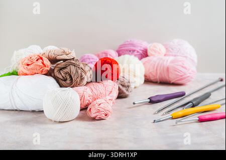 Su un tavolo ci sono tantissimi filati colorati, ganci all'uncinetto e aghi per maglieria Foto Stock