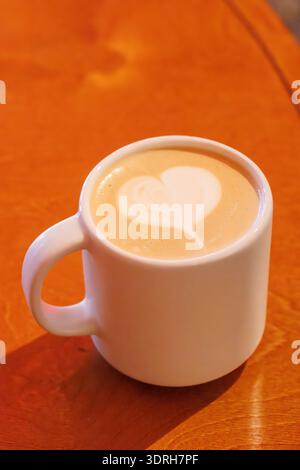 Riscaldare il cappuccino in una tazza con una latte art a forma di cuore Foto Stock