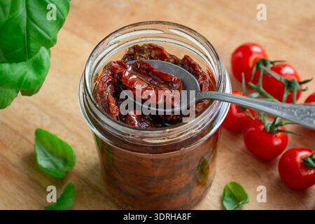Pomodori secchi al sole con olio d'oliva in vaso di vetro, messa a fuoco selettiva Foto Stock
