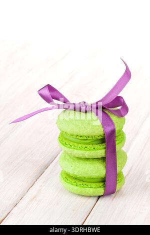 Macaron verde con nastro viola bianco sul tavolo di legno con lo spazio di copia Foto Stock