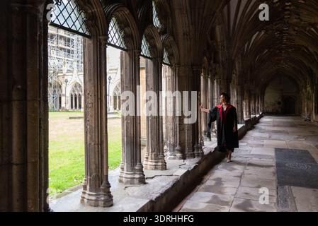 Donna studentessa in abito accademico in piedi in un'antica chiesa gotica che rappresenta una pietra miliare dell'istruzione e l'architettura storica. Cattedrale di Canterbury Ken Foto Stock