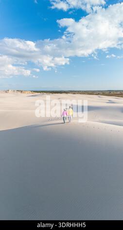 Coppia che cammina mano nella mano su una spiaggia tranquilla in Danimarca sotto un cielo blu brillante Foto Stock