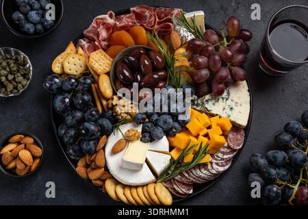 Stuzzichini con formaggi assortiti, carne, uva e noci. Vassoio di salumi e formaggi. Foto Stock