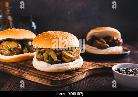 Appetitosi hamburger con funghi grigliati ed erbe aromatiche su un asse di legno Foto Stock