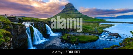 Il monte Kirkjufell sorge drammaticamente sullo sfondo di un vibrante tramonto del sole di mezzanotte in Islanda Foto Stock