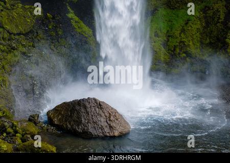 Maestosa cascata di Kvernufoss che scende dalla scogliera rocciosa nel lussureggiante paesaggio verde delle Icelands Foto Stock