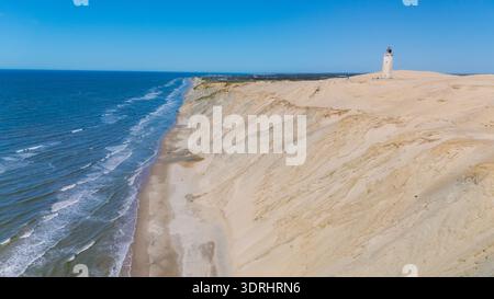 Esplora la suggestiva costa della Danimarca, dove le dune di sabbia dorata si incontrano con il vivace oceano blu Foto Stock