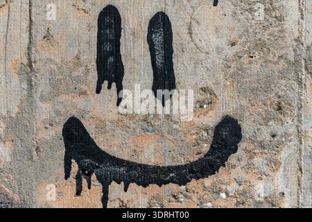 Vernice spray nera Smiley Face Graffiti su pareti in cemento armato Foto Stock