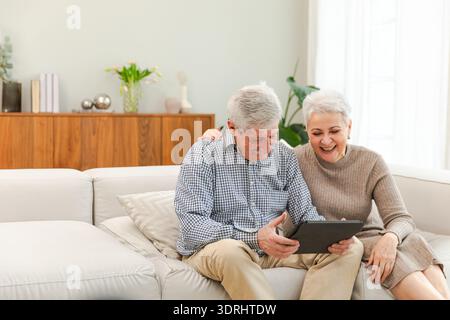 Coppia anziana con tablet che guarda video online. Marito moglie che passa del tempo insieme a casa. Felice moderno e maturo Foto Stock