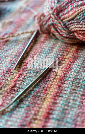 Confortevole scena di lavorazione a maglia fatta a mano con palline colorate in filato di lana e aghi in legno. Foto di alta qualità Foto Stock
